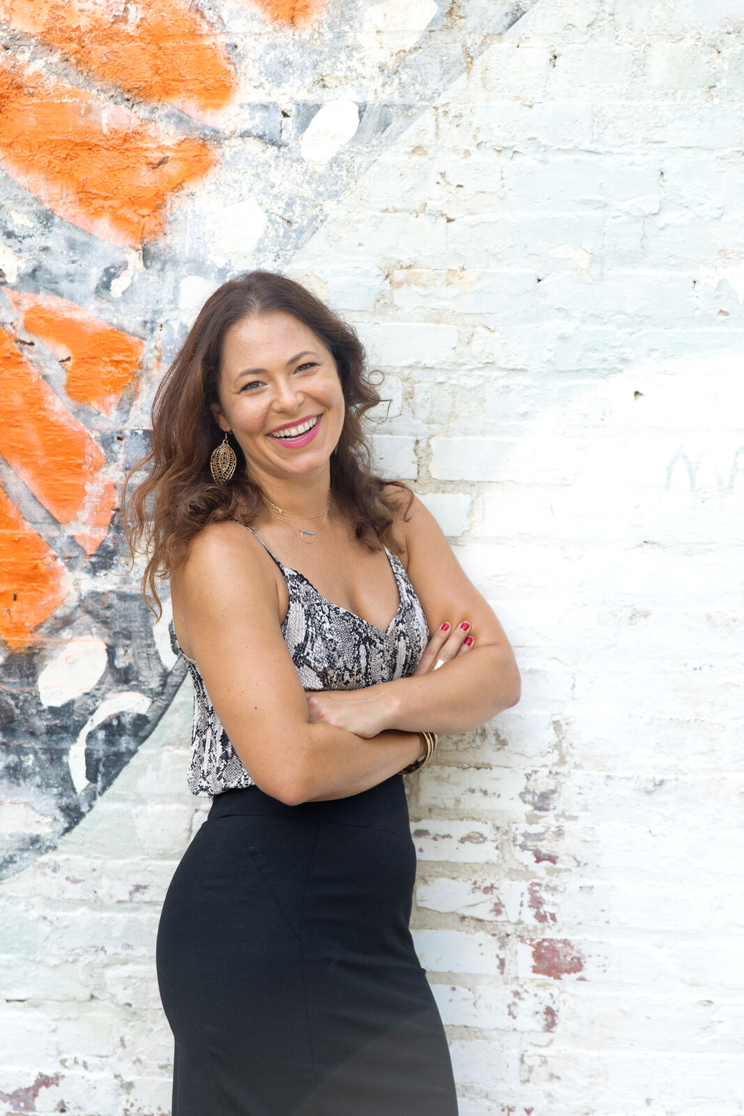 Erin leaning against a painted brick wall