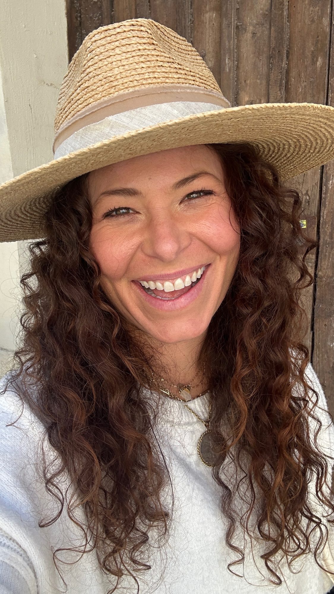 Erin in a straw hat, laughing at the camera